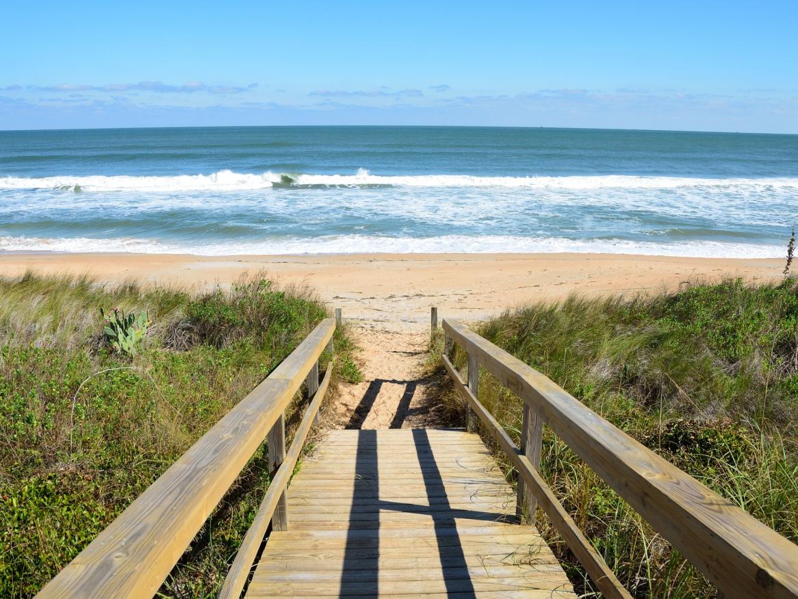 photo of a boardwalk down to the beach with sea in the distance