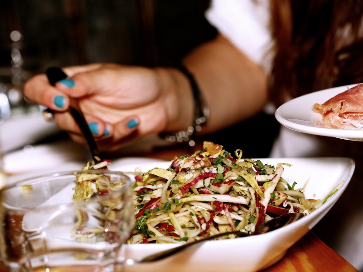 Photo of a plate of food, hands by the side lifting food from main plate to side plate
