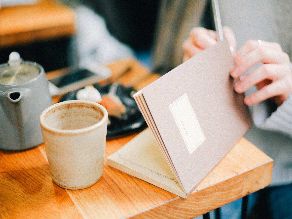 A person opening a journal on a table.