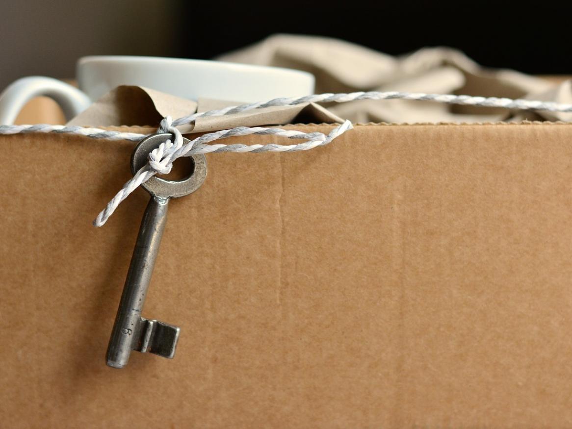 A key on a string is dangling on the edge of a cardboard box.