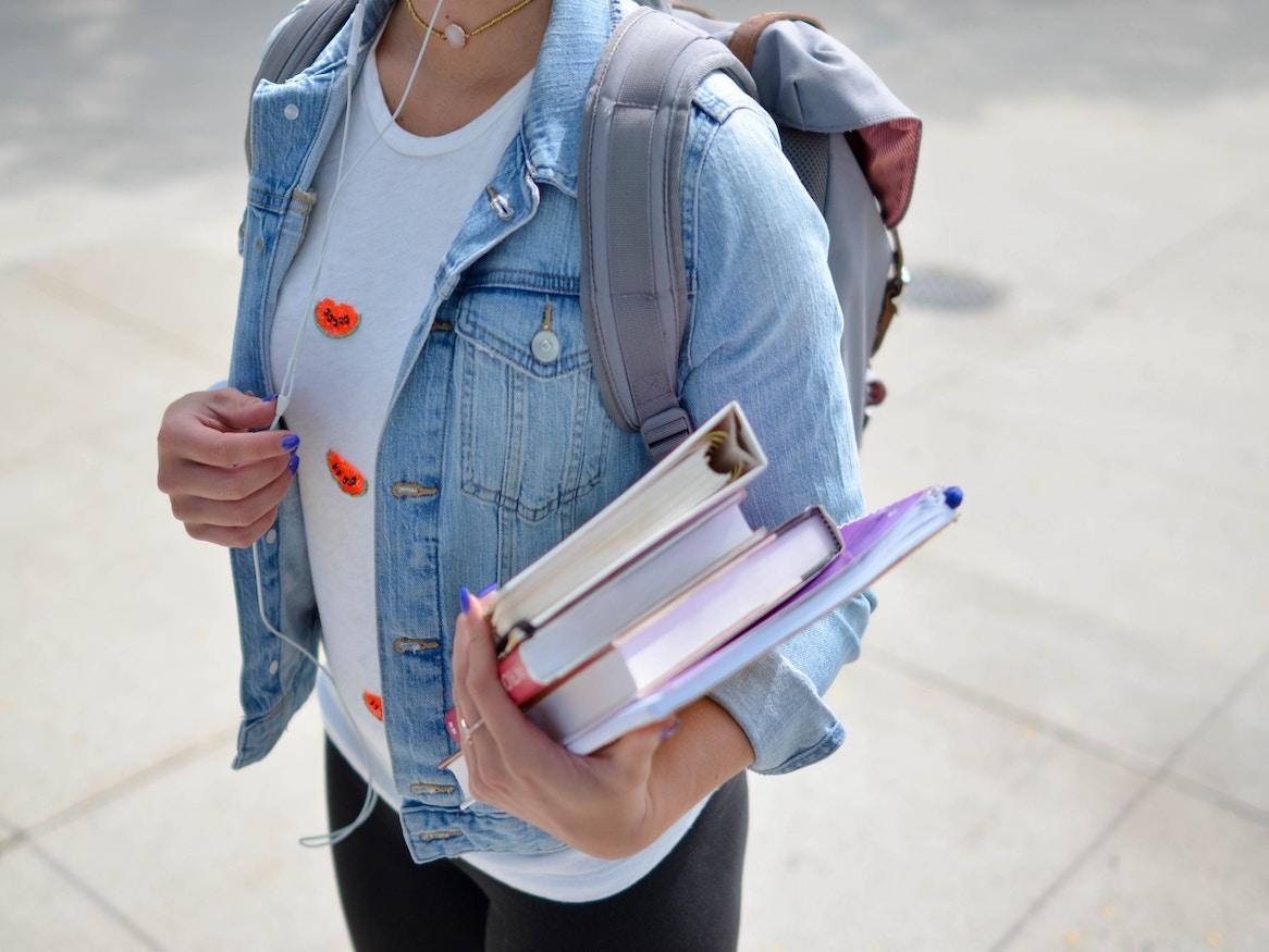 Person carrying books and backpack.