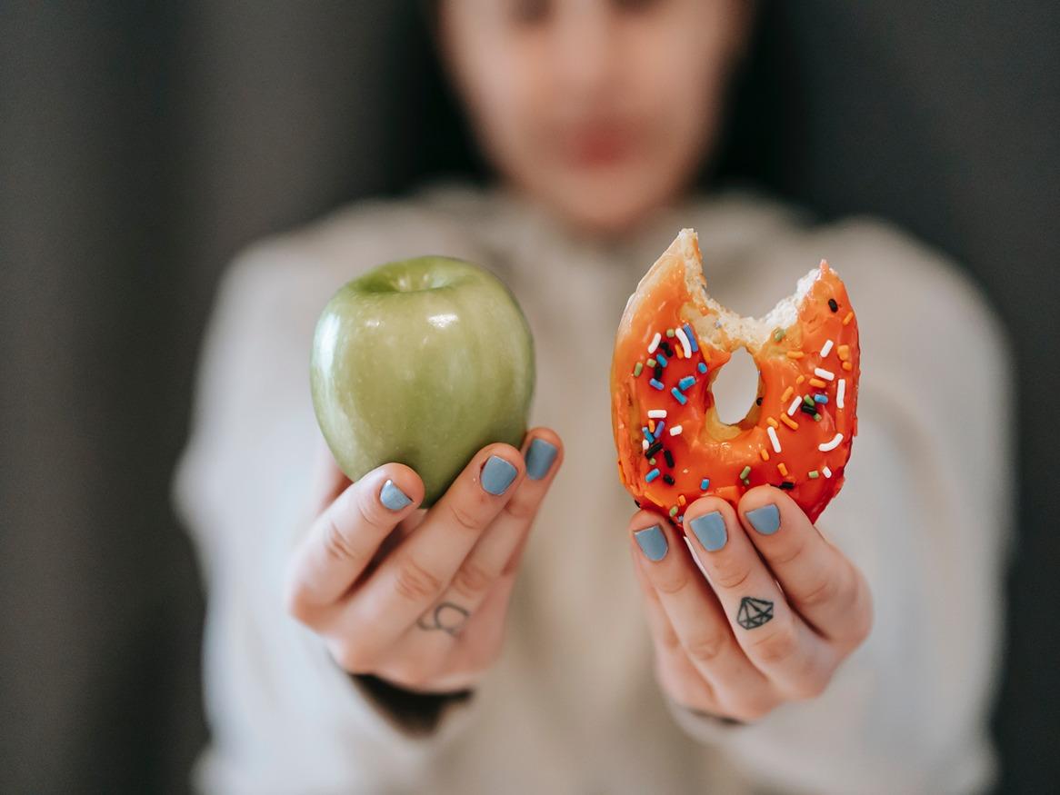the woman holding an apple and donut