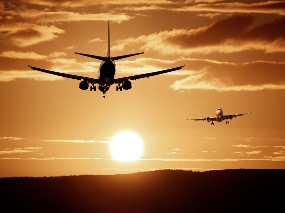 A plane flies in a sunset sky.