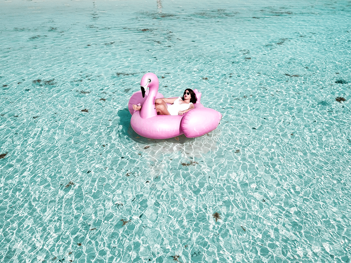 A woman floating in a flamingo floaty in the ocean