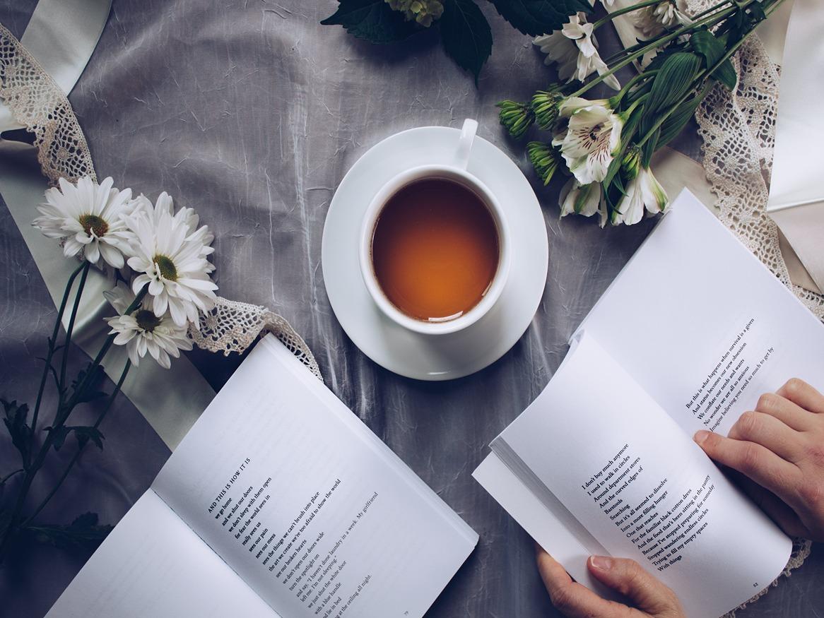 A birds-eye view of a table with a coffee, books and bouquets of flowers on it