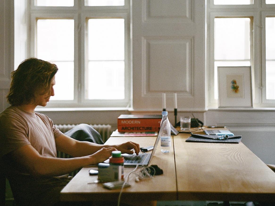 Man sitting at a table at home working on a laptop