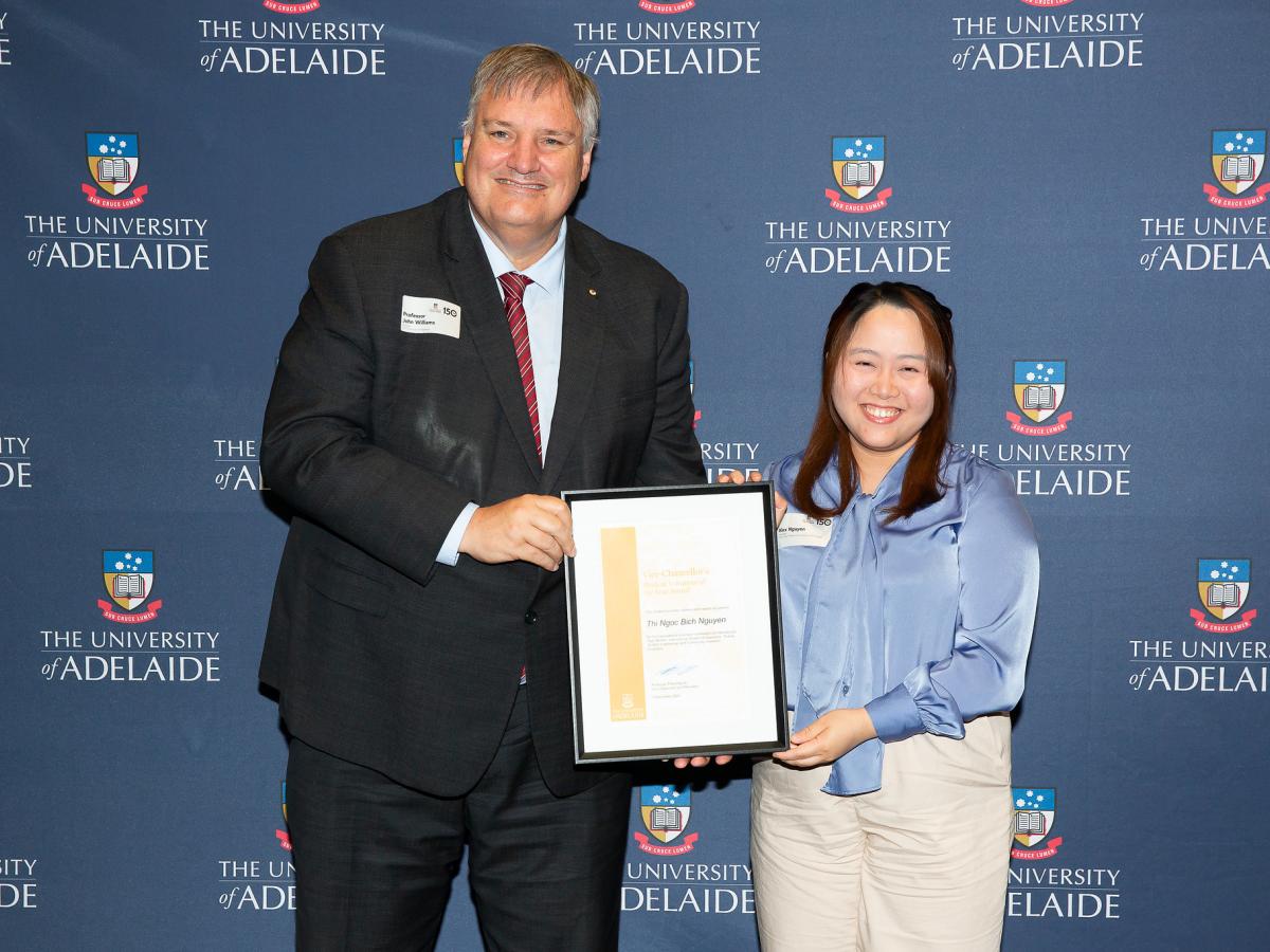 A photo of Alex Nguyen accepting award from Provost John Williams AM